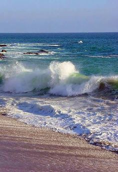 the waves are crashing on the sandy beach