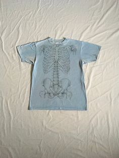 "vintage 1980s t-shirt Hanes Fifty-Fifty, made in USA cotton/polyester bend single stitch light smoky blue w/black front/back skeletal anatomy print w/names of bones marked- Leslie Arwin, 1970, Athletic Supporter Ltd, Livonia, Mich. good vintage condition w/bleach stain fade/pilling-see photos fits most like a x-small to small(labeled M)-see below measures, lying flat, shoulder-16 1/2\" sleeve-6 1/2\" chest-17 1/2\" length-25\"" Fitted Acid Wash T-shirt With Graphic Print, Fitted Acid Wash T-shirt, Fitted Acid Wash Short Sleeve T-shirt, Vintage Cotton Tops With Skull Print, Vintage Fitted T-shirt For Streetwear, Fitted Vintage T-shirt For Streetwear, Vintage Short Sleeve T-shirt With Skull Print, Fitted Distressed T-shirt With Crew Neck, Distressed Fitted Crew Neck T-shirt