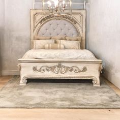 a white bed sitting on top of a wooden floor next to a wall mounted mirror