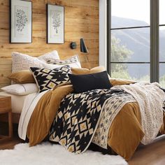 a bed in a bedroom with wooden walls and floor to ceiling windows overlooking the mountains