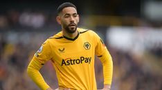 a man standing on top of a soccer field wearing a yellow uniform and holding his hands on his hips