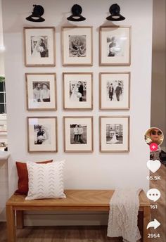 a room with many pictures hanging on the wall and a bench in front of it