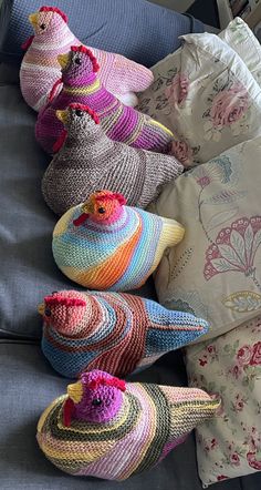 crocheted hats and pillows are arranged on a blue couch with floral print sheets