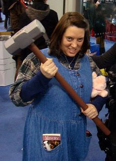 two women dressed in costumes and holding an ax, standing next to each other on a blue carpeted floor