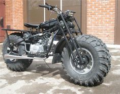 a motorcycle parked in front of a brick building with large tires on it's sides