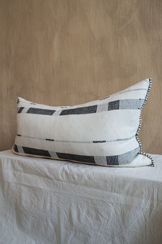 a white and black pillow sitting on top of a bed next to a brown wall