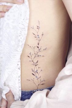 a woman's stomach with a small flower tattoo on it