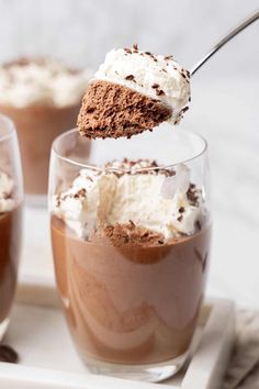 two desserts with chocolate and whipped cream on top are being spooned into each other