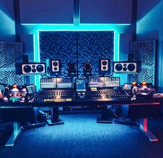 a recording studio with several monitors and sound equipment on the desk, all lit up by blue lights