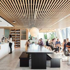 a group of people sitting around a table in a room with lots of shelves and chairs