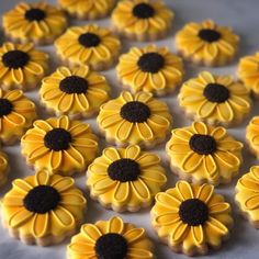 some yellow and black decorated cookies are on a white tablecloth with flowers in the middle