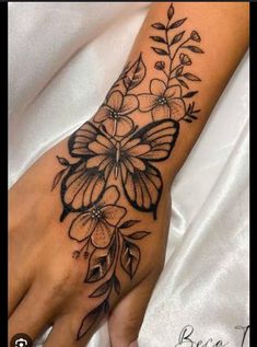 a woman's hand with flowers and leaves on the left side of her arm