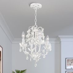 a chandelier hanging from the ceiling in a living room with white walls and flooring