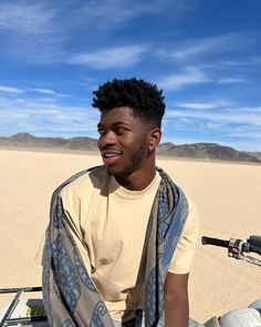 a young man sitting on top of a motorcycle in the middle of an empty desert