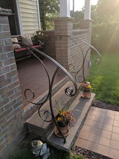 an iron railing on the front steps of a house with flowers and potted plants