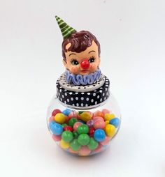 there is a small toy clown sitting on top of a bowl of gummy balls