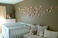 a baby's room decorated in white and grey with butterflies on the wall above the crib