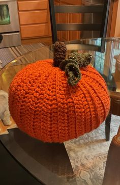 an orange knitted pumpkin sitting on top of a glass table in front of a stove