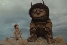 a woman sitting on top of a rock next to a giant stuffed animal