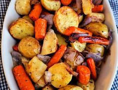 a bowl filled with potatoes and carrots on top of a blue checkered table cloth