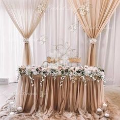 a table with flowers and candles on it in front of a curtained backdrop at a wedding