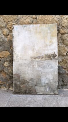 an old painting is on display in front of a stone wall that has been stripped off