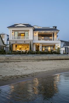 a large white house sitting on top of a sandy beach next to the ocean at night