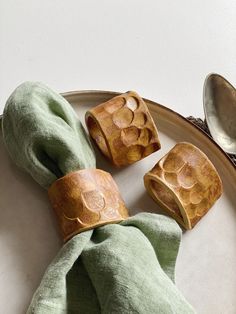 wooden dices are sitting on a plate next to a green napkin and silver spoon