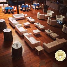 a large room filled with lots of white couches and round tables on top of wooden floors