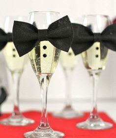 four wine glasses with black bow ties on them are sitting on a red tablecloth