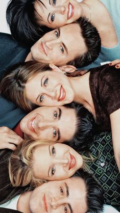 four people are laying down together on the bed and looking at the camera with smiles