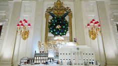 a large white building with a christmas wreath on the wall and lights hanging from the ceiling