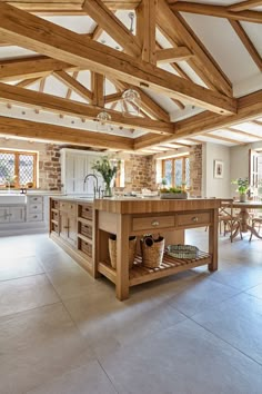 a large kitchen with an island in the middle and wooden beams on the ceiling above it