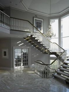 a large foyer with marble flooring and stairs leading up to the second story window