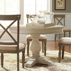 a dining room table with two chairs and a pitcher on it's centerpiece