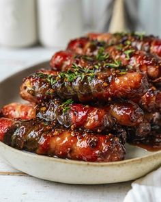 a plate full of meat covered in sauce and garnished with green sprigs