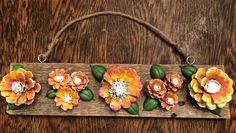 a wooden sign with flowers painted on the front and back of it, hanging from a rope