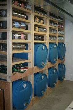 several blue barrels are lined up on the wall in a storage area with shelves holding various types of cans