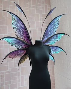 a black mannequin with purple and green butterfly wings on it's head