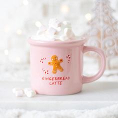 a pink mug filled with marshmallows and a gingerbread latte on top