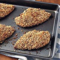 four pieces of chicken on a baking sheet with seasoning sprinkled on top