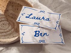 two pieces of paper with the words laura and bon written on them sitting in a bowl