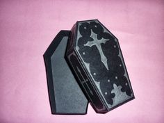 an open box with a cross on it sitting on top of a pink tablecloth