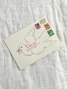 an envelope with stamps on it and a drawing of a bird holding a flower in its beak