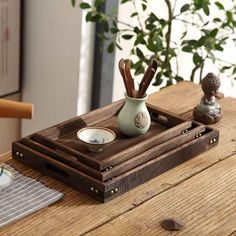 a wooden tray with two cups and spoons in it on top of a table