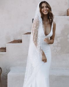 a woman in a white wedding dress and veil posing for the camera with her hand on her hip