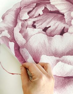 a person is painting a large flower with watercolors