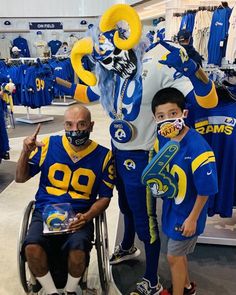 two boys in blue and yellow jerseys posing for a photo with a man in a wheel chair