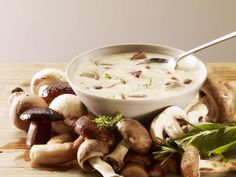 a bowl of soup surrounded by mushrooms and herbs