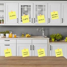 post - it notes are stuck to the cabinets in a kitchen with white cupboards